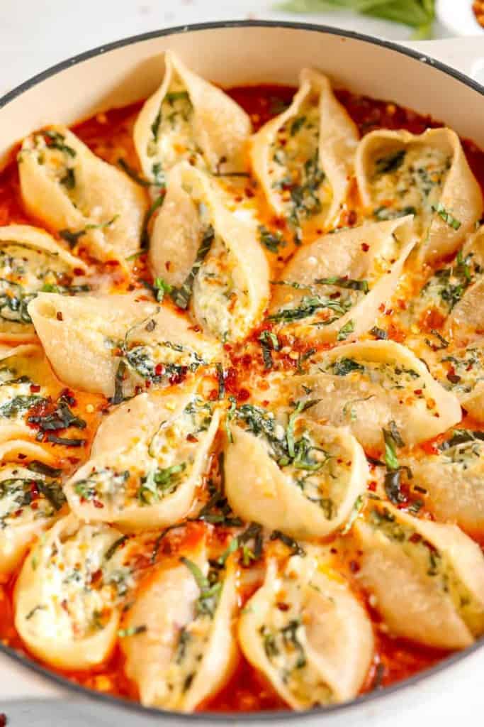 close up of stuffed pasta shells in red sauce
