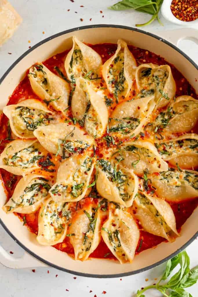 overhead of stuffed pasta shells in red sauce with fresh basil 