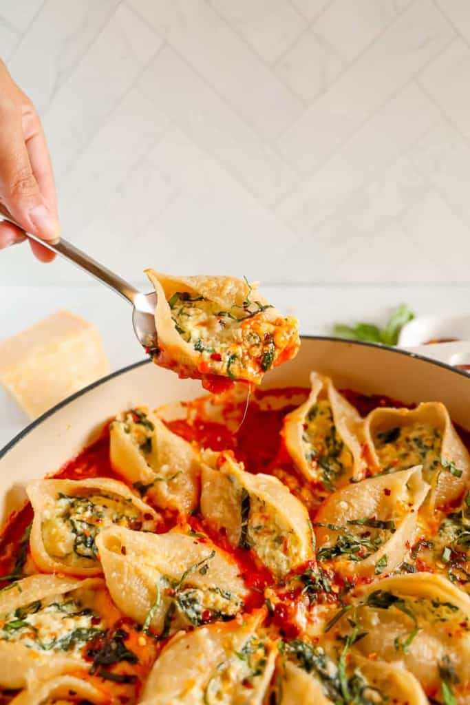 stuffed pasta shell being lifted out of baking dish with a spoon
