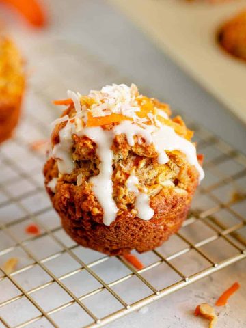 carrot cake muffin with glaze dripping off side on a gold stand