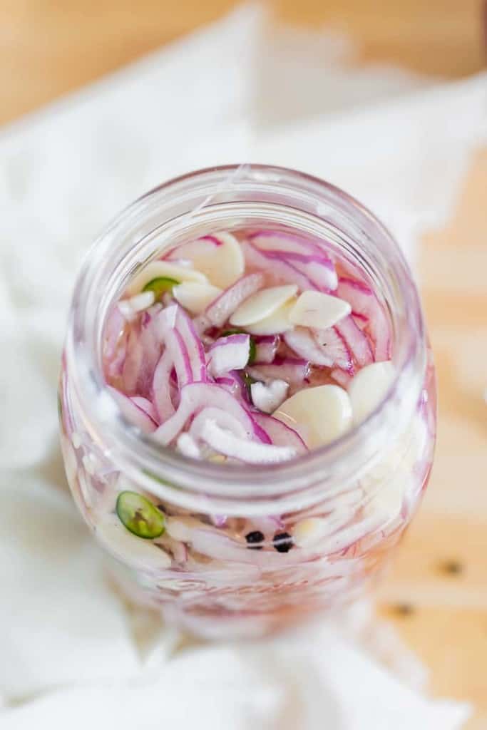 sliced red onion, pepper, and garlic in a glass jar