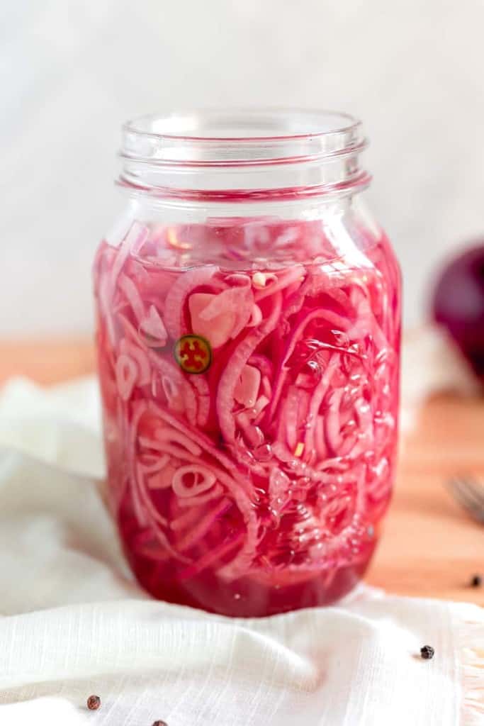 glass jar of pickled red onions on a white cloth