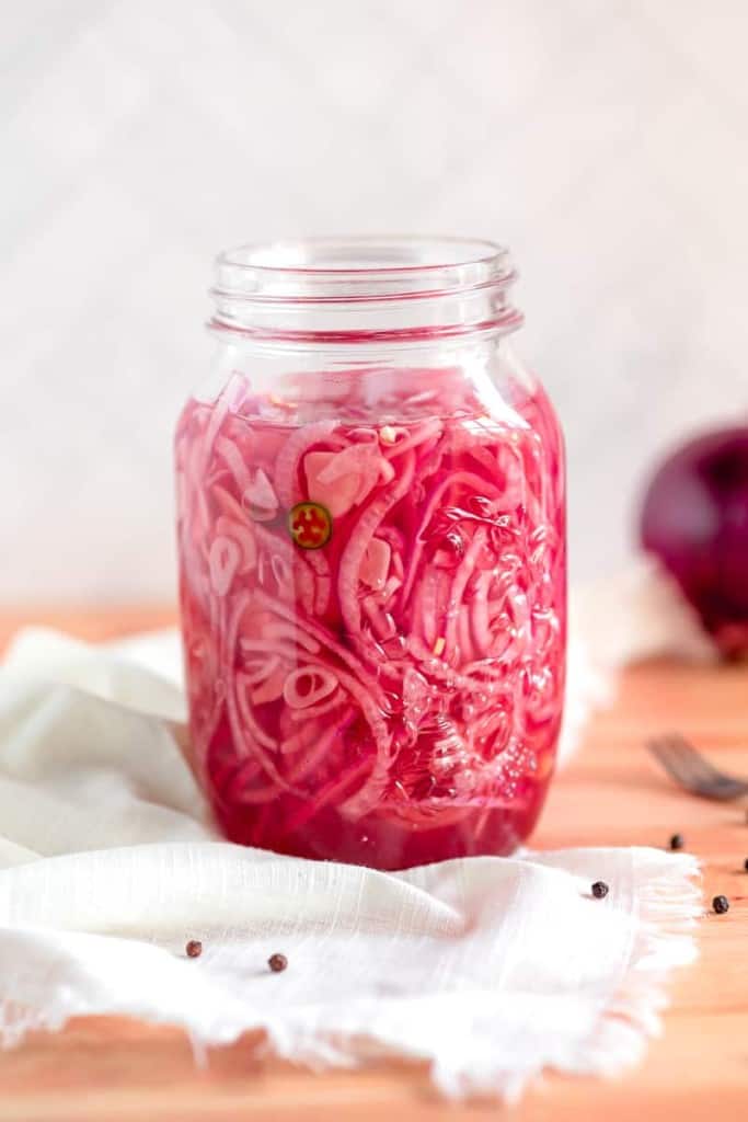 glass jar of pickled red onions on a white cloth
