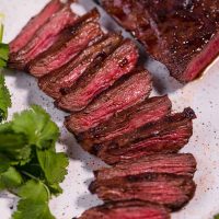 close up of sliced carne asada steak on white plate