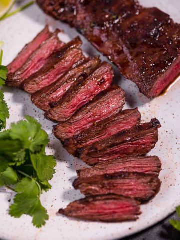 close up of sliced carne asada steak on white plate