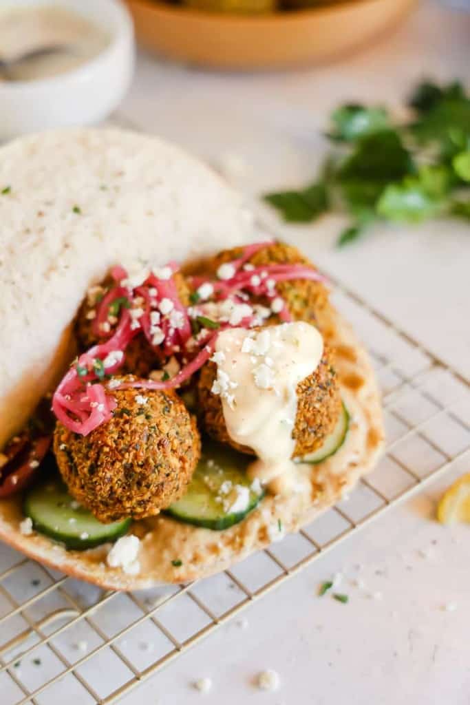 homemade falafel in a pita topped with pickled red onions and tahini sauce