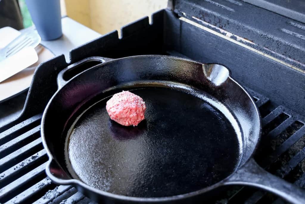 raw burger on cast iron on a grill