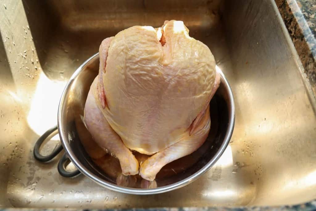 whole chicken in a bowl in the sink
