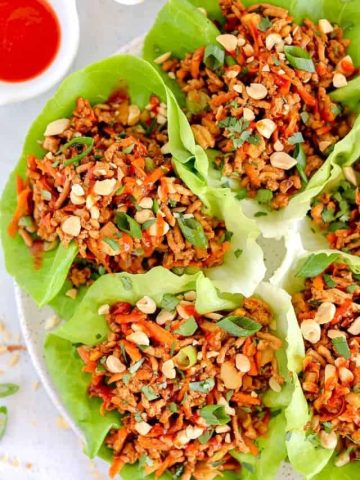 chicken lettuce wraps with sriracha drizzled and chopped peanuts on top
