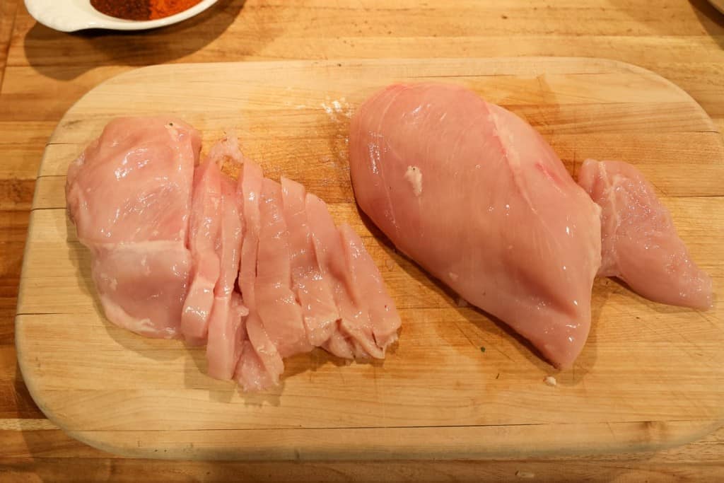 slicing chicken breast on a cutting board