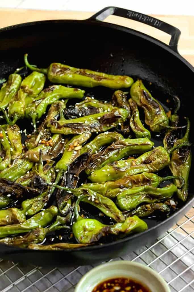 blistered shishito peppers in a cast iron skillet