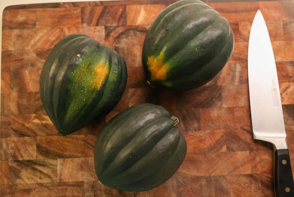 3 squashes whole on a wooden cutting board