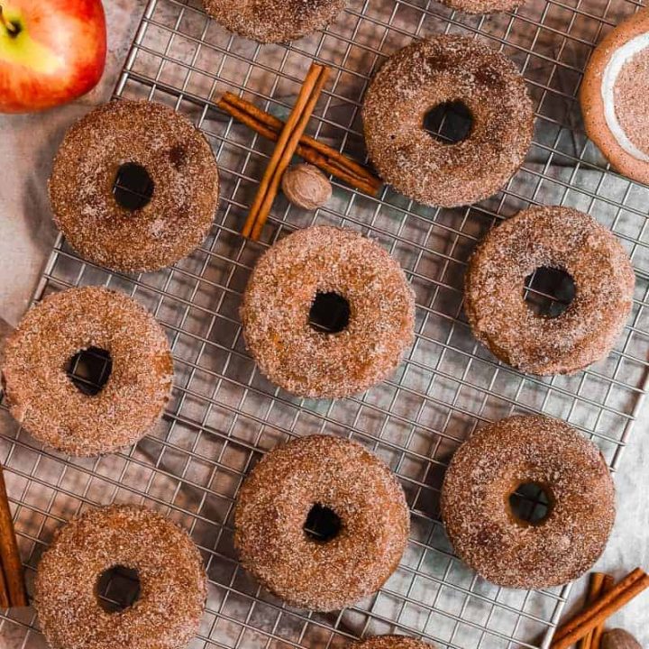 apple cider donuts covered in cinnamon sugar on a cooling rack