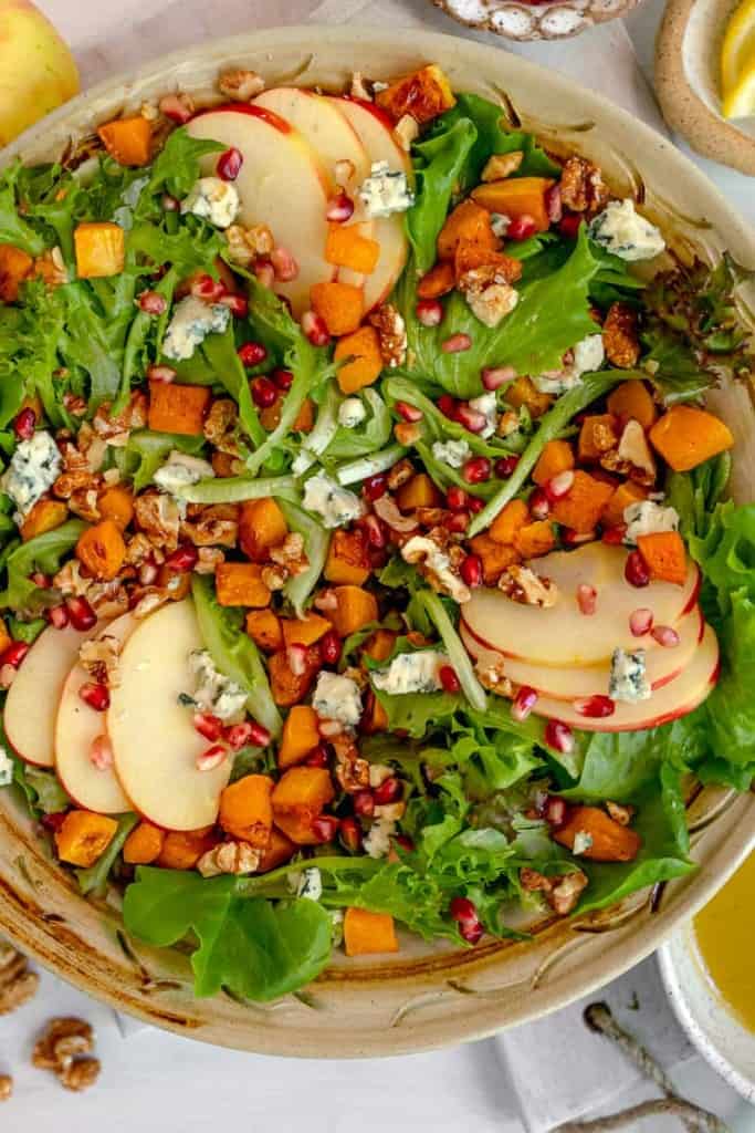 mixed green salad with sliced apples, roasted butternut squash, blue cheese crumbles, and candied walnuts