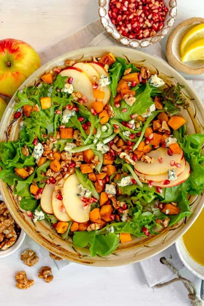 overhead photo of fall harvest salad with roasted squash, sliced apples, walnuts and blue cheese crumbles