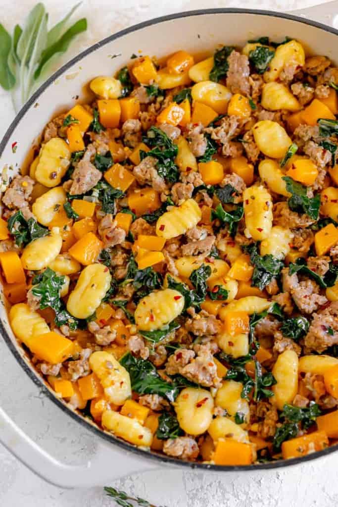 close up of gnocchi, diced butternut squash, sausage, and kale in a skillet 