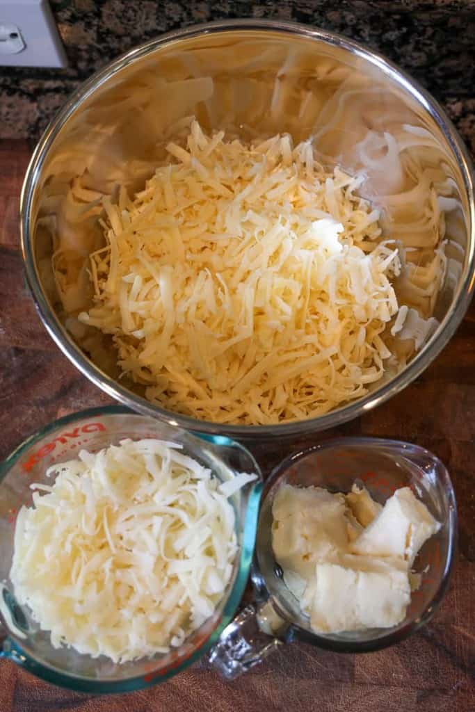shredded guyere, shredded cheddar, and cubed brie cheese in bowls