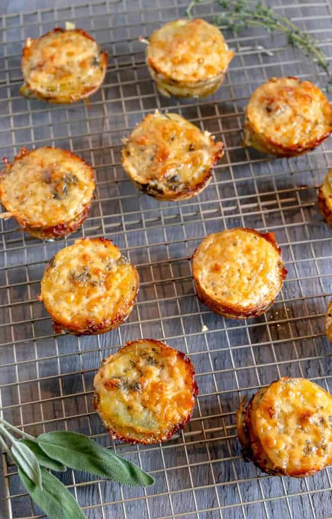 cheesy potato stacks on a cooling rack with sage and thyme
