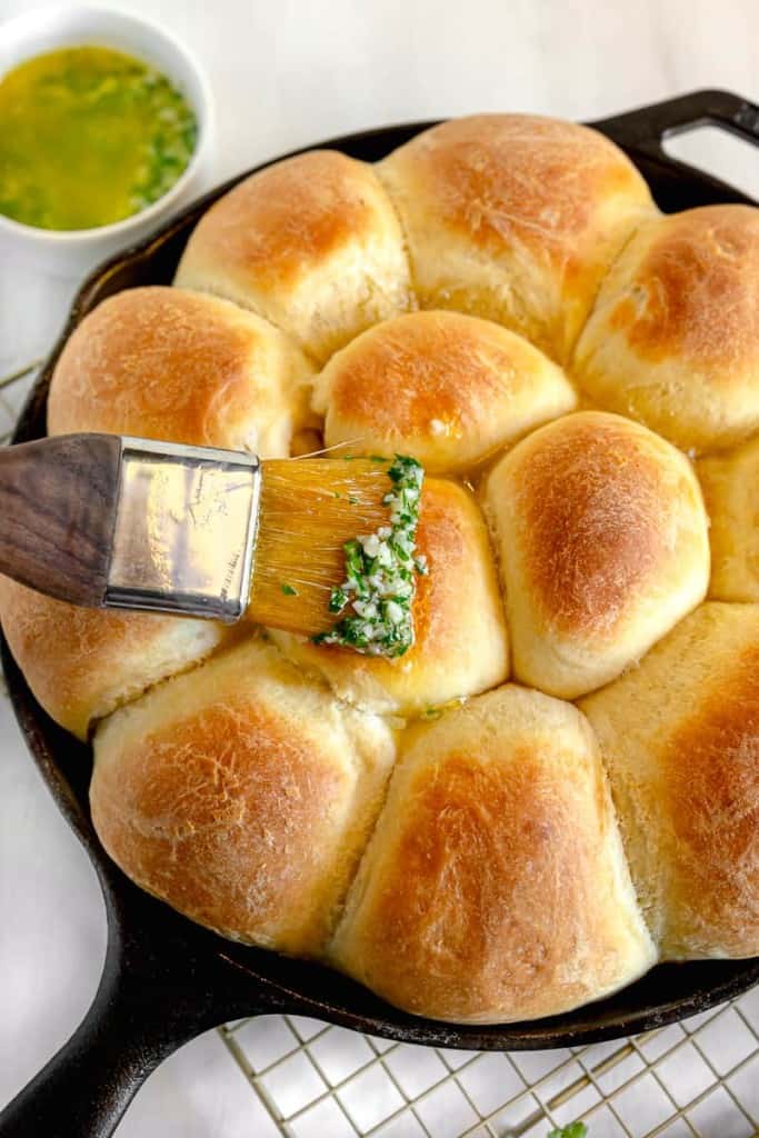 brushing tops of dinner rolls with garlic herb butter