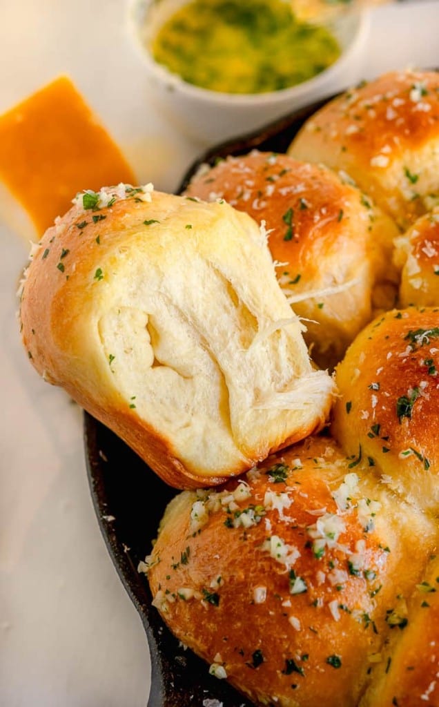 side view of a garlic butter dinner roll on a cast iron skillet