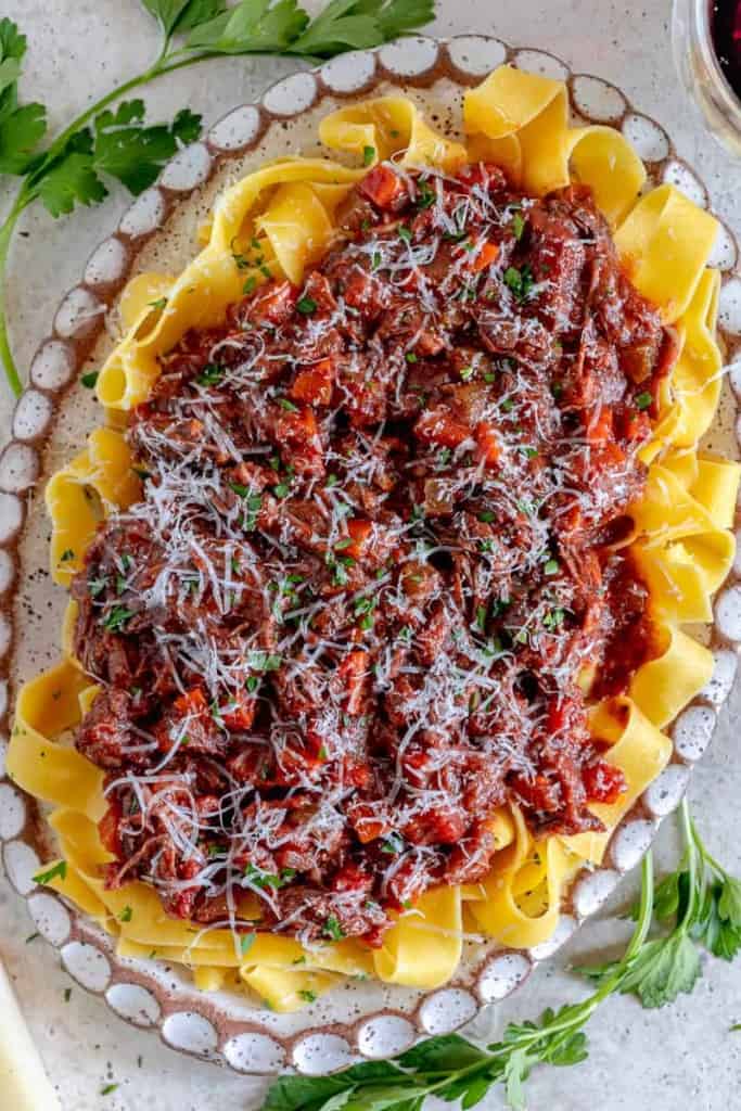 beef short rib ragu sauce over pappardelle pasta with grated cheese on top