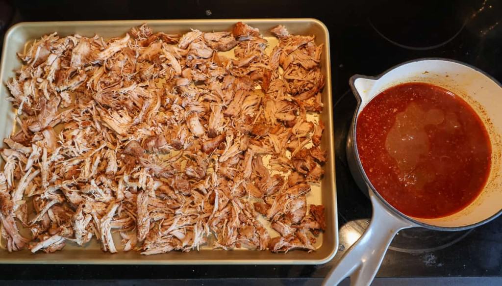 sheet pan with pork carnitas and side pot full of sauce