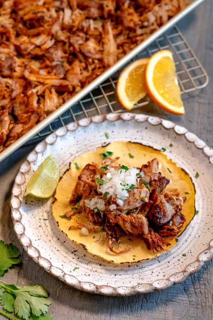 corn tortilla with carnitas, minced onion and lime wedges