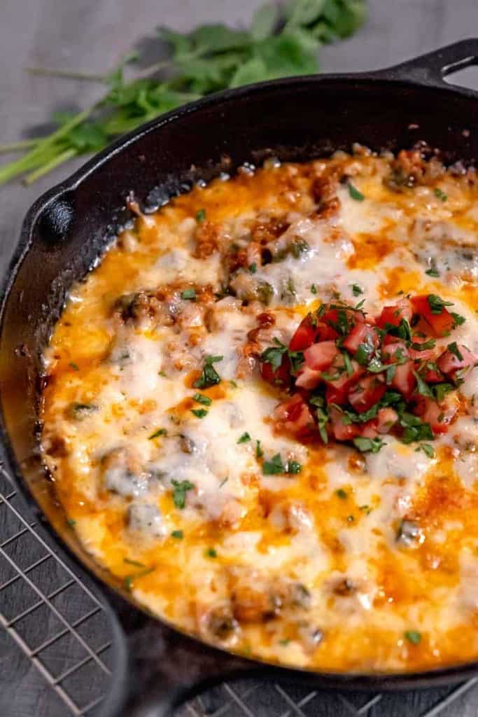 queso fundido in a cast iron skillet topped with diced tomatoes