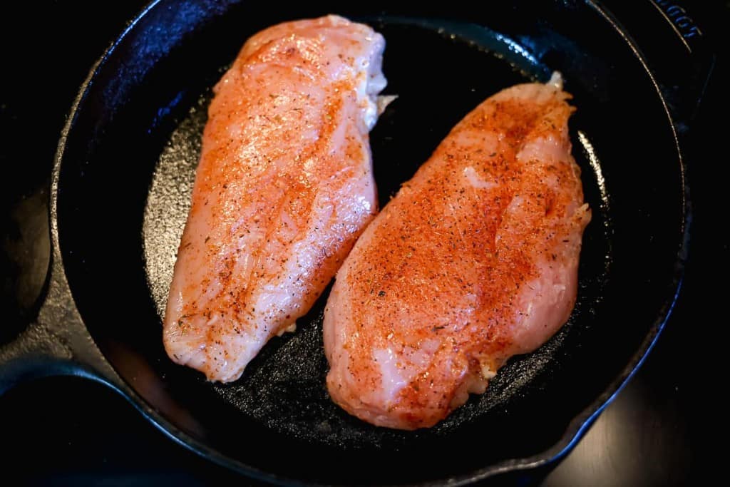 two chicken breast in a cast iron skillet on the stovetop