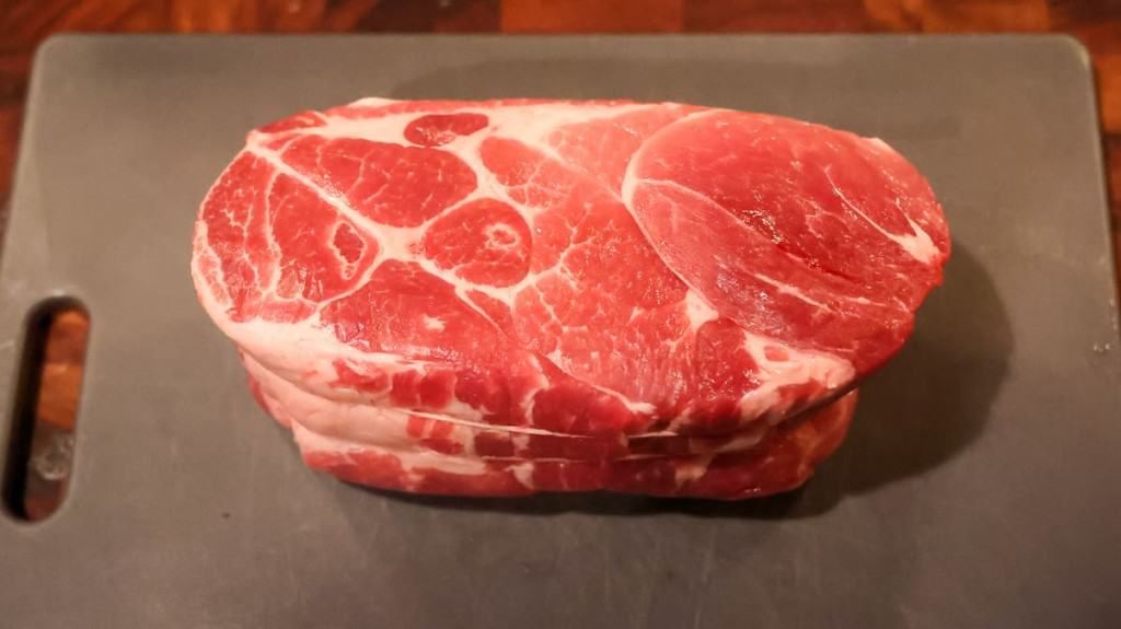 raw pork shoulder on a grey cutting board