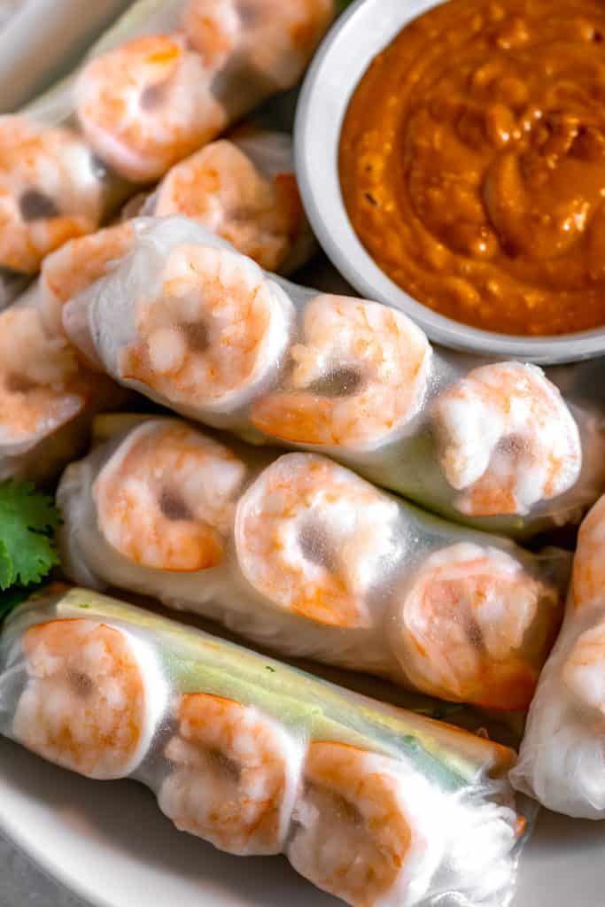 close up of shrimp wrapped in rice paper next to a bowl of spicy peanut sauce