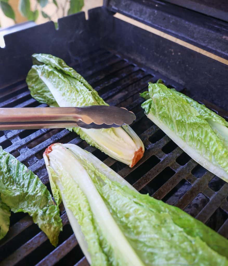 using tongs to push grilled romaine on grill 