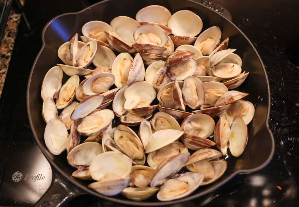 open clams in a cast iron skillet on the stovetop