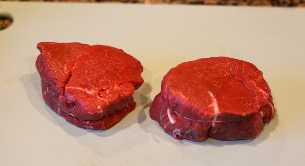 two filet mignons on a blue cutting board