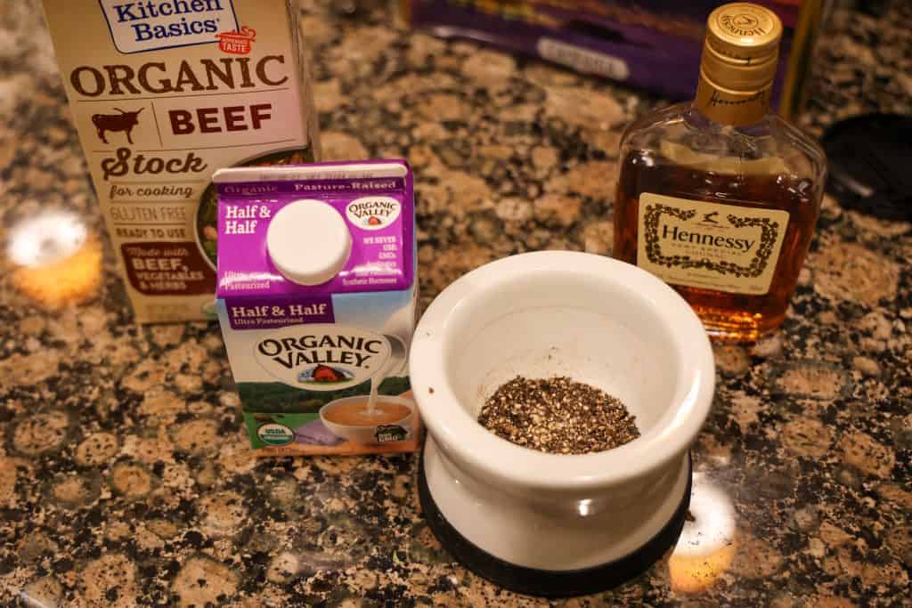 beef stock box, carton of half and half, black peppercorns, and cognac bottle on kitchen counter