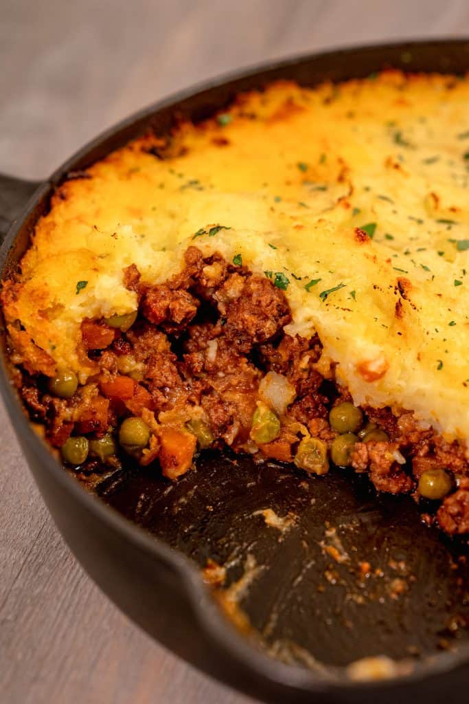 open section of shepherds pie in a cast iron skillet displaying the lamb stuffing inside the skillet