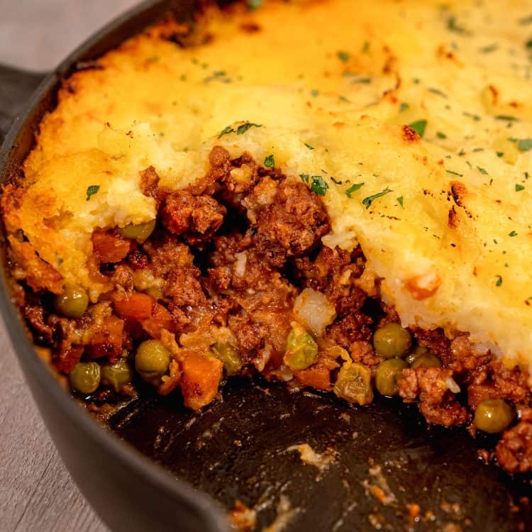 open section of shepherds pie in a cast iron skillet displaying the lamb stuffing inside the skillet