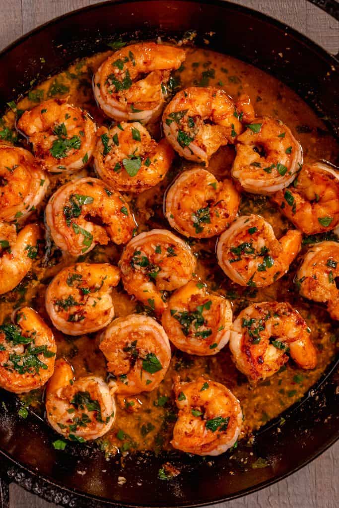 shrimp scampi in a cast iron skillet on a wooden background