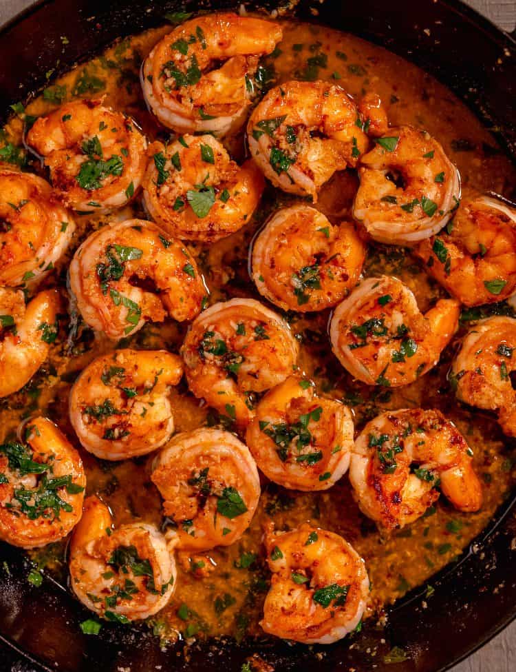 shrimp scampi in a cast iron skillet on a wooden background