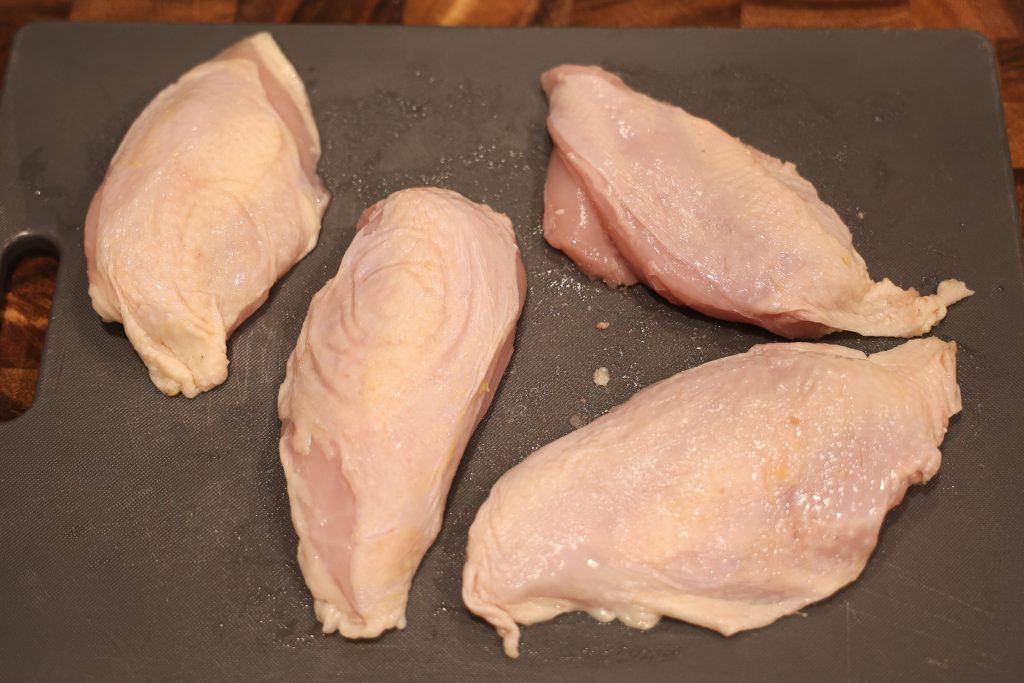 4 skin on chicken breast on a grey cutting board
