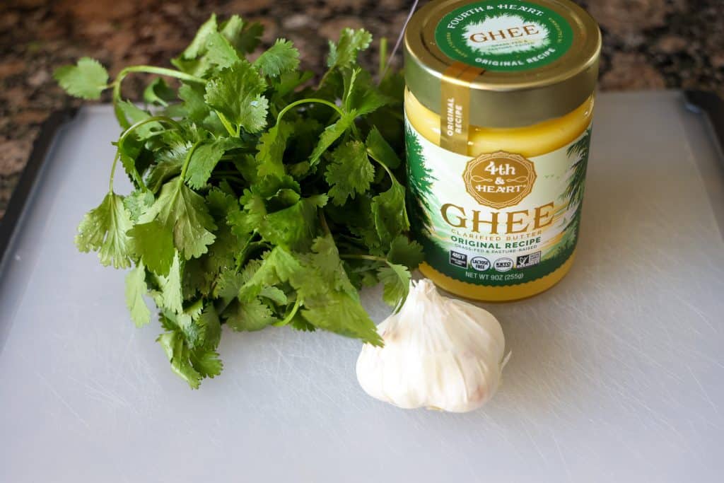 garlic, ghee, and fresh cilantro on top of a cutting board
