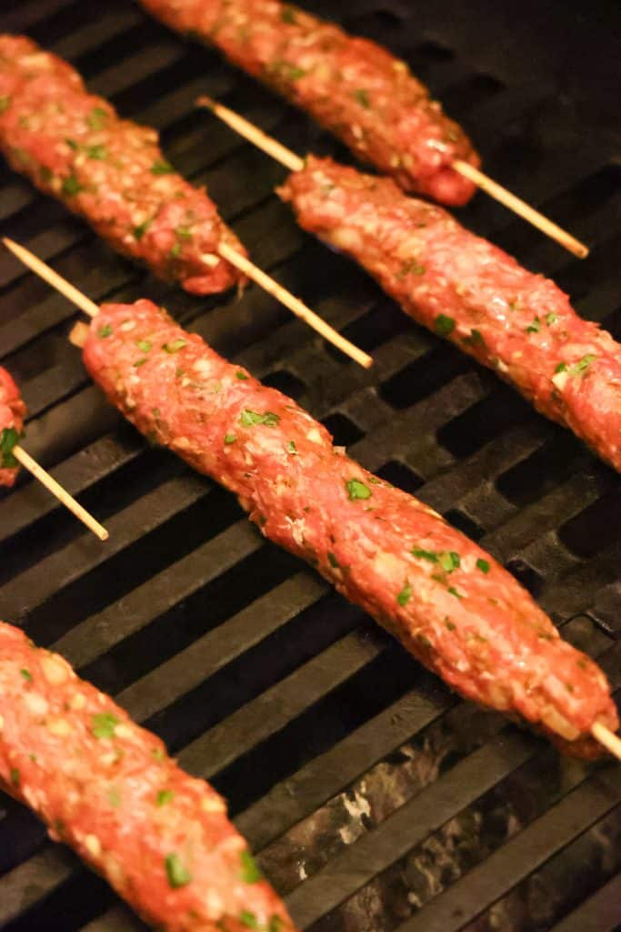 an uncooked kofta kabob on grill grates