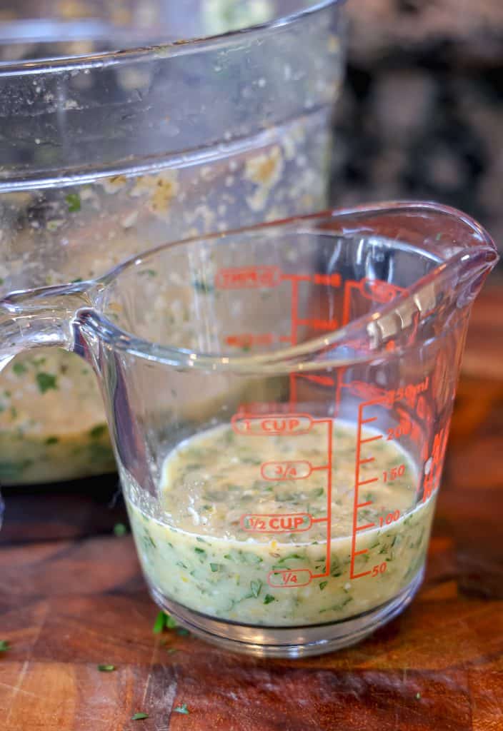 measuring cup on a wooden cutting board with mojo marinade inside