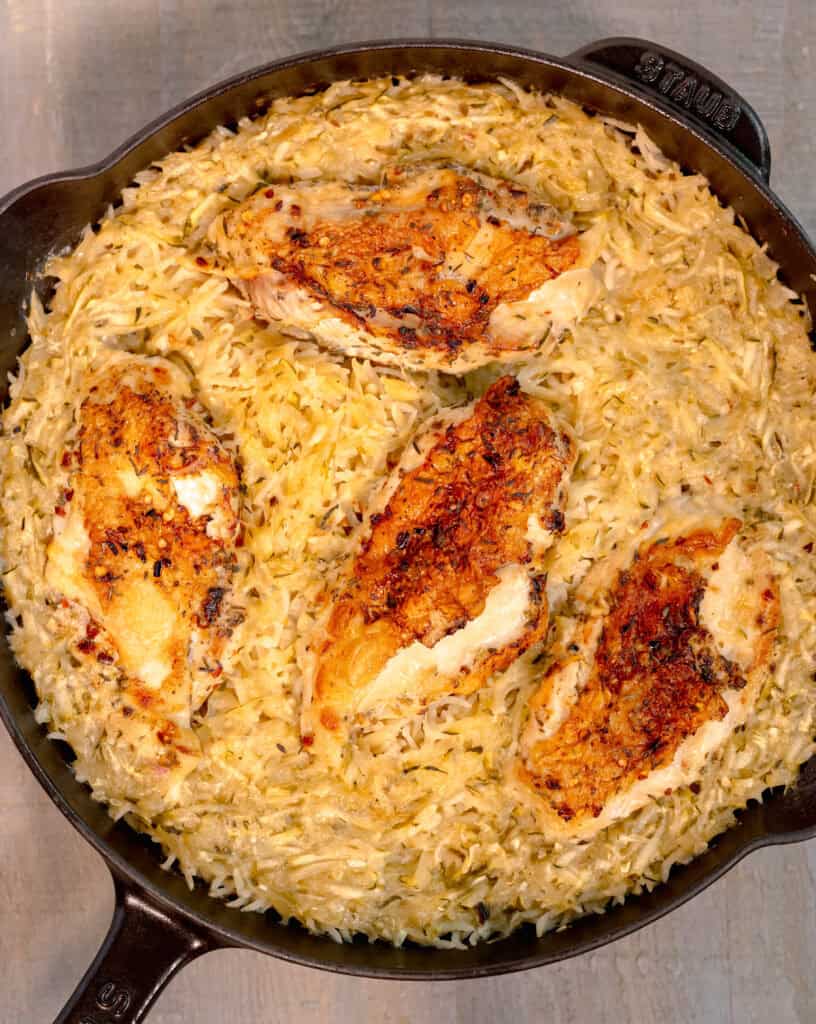 chicken and zucchini rice pilaf in a cast iron skillet on a wooden background